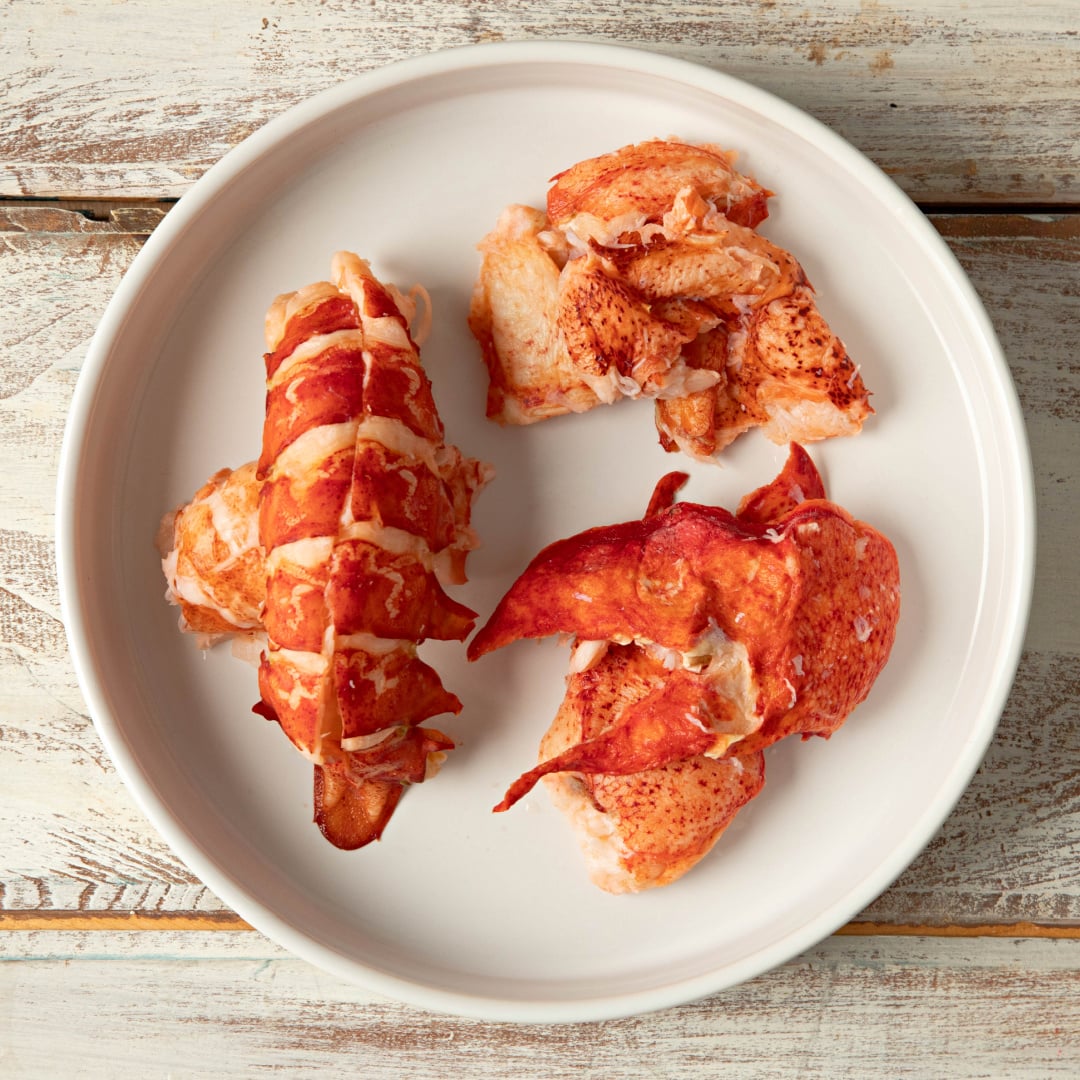 Cooked Maine lobster tail, claw, and knuckle meat arranged separately on a plate