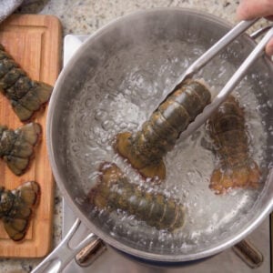 Add Lobster tails to boiling water with tongs.