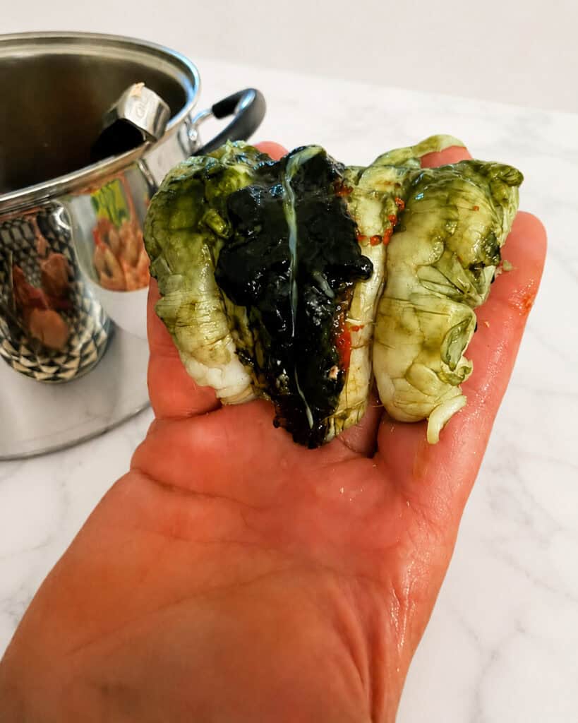 Opened lobster tail showing dark roe, green tomalley, and natural digestive material.