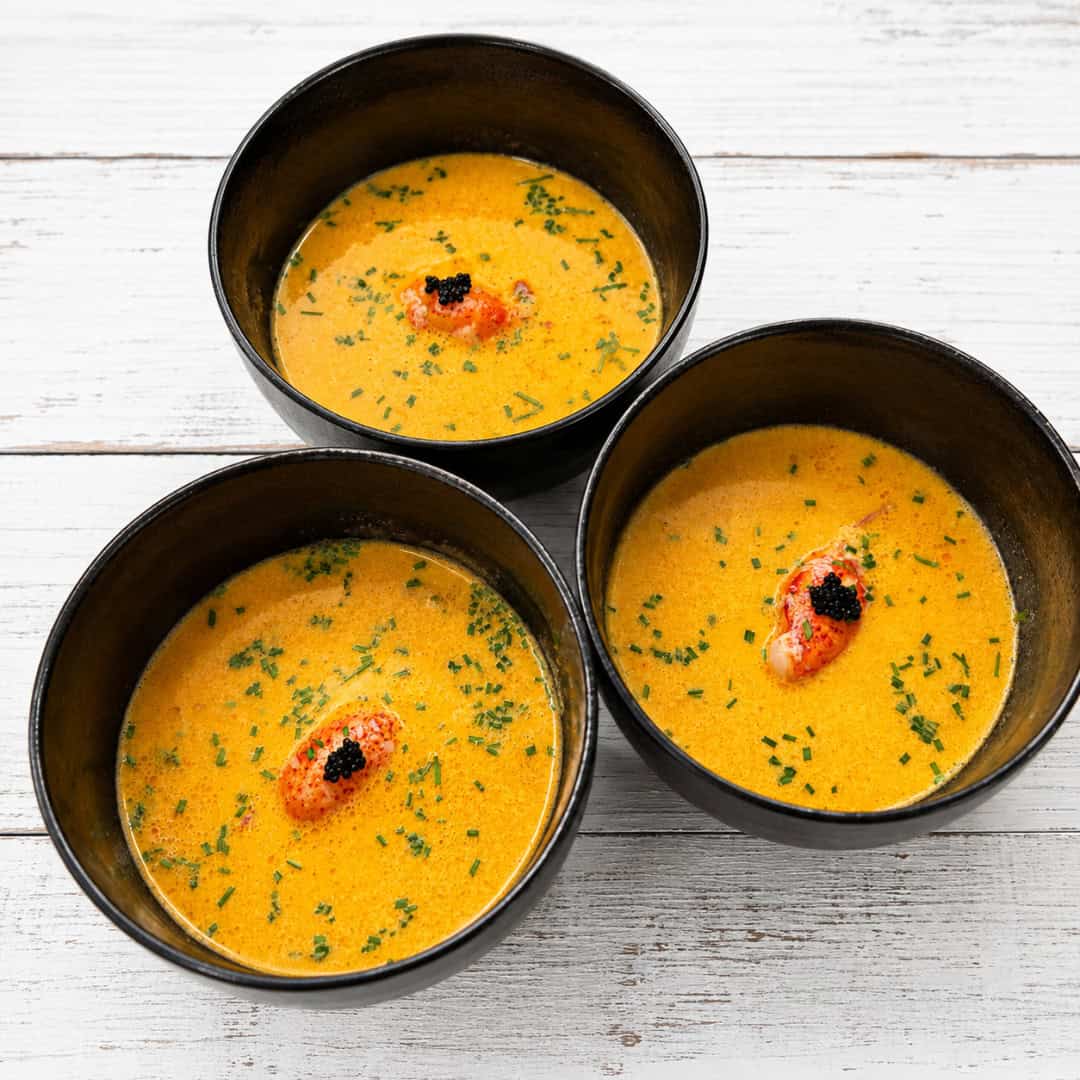 Three bowls of creamy gluten-free lobster bisque topped with lobster meat, chives, and caviar, with an easy alcohol-free option.